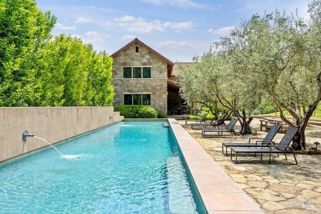 view of pool with a patio area and pool water feature