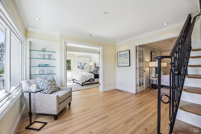 sitting room with built in features, ornamental molding, and light wood-type flooring