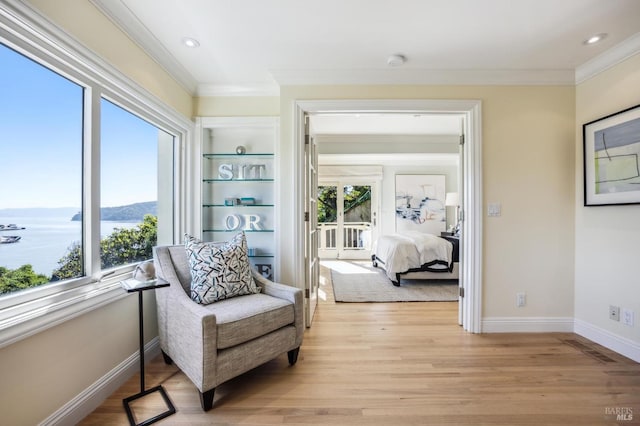 living area featuring ornamental molding, light wood-type flooring, a water view, and built in features