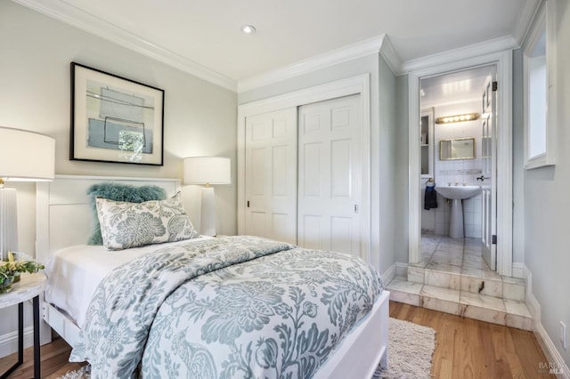 bedroom featuring wood-type flooring, ensuite bathroom, a closet, and ornamental molding