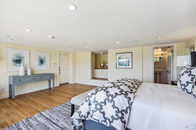 bedroom with ensuite bathroom and light wood-type flooring