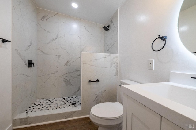 bathroom featuring vanity, toilet, wood finished floors, and a marble finish shower