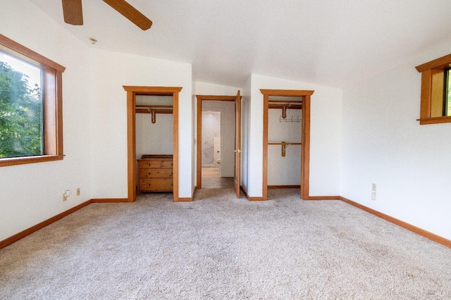 unfurnished bedroom featuring baseboards, two closets, ceiling fan, and carpet flooring