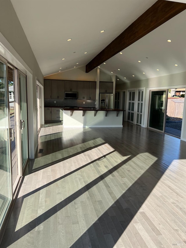 interior space with stainless steel appliances, dark wood-type flooring, beamed ceiling, and dark brown cabinets