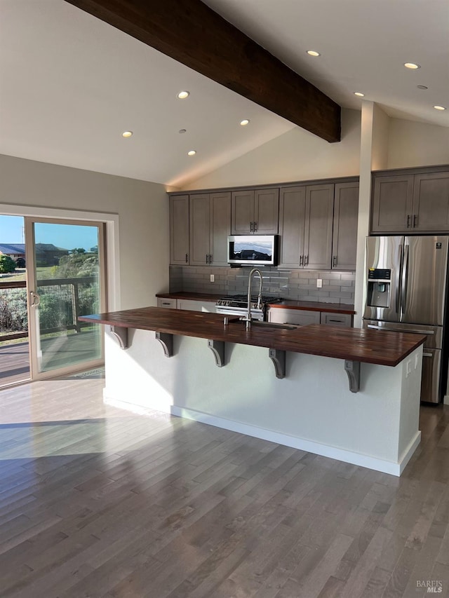 kitchen with appliances with stainless steel finishes, lofted ceiling with beams, and dark hardwood / wood-style floors