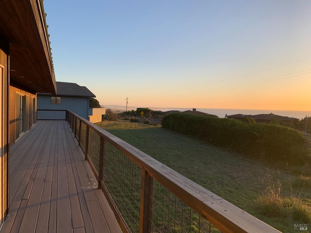 deck at dusk featuring a lawn