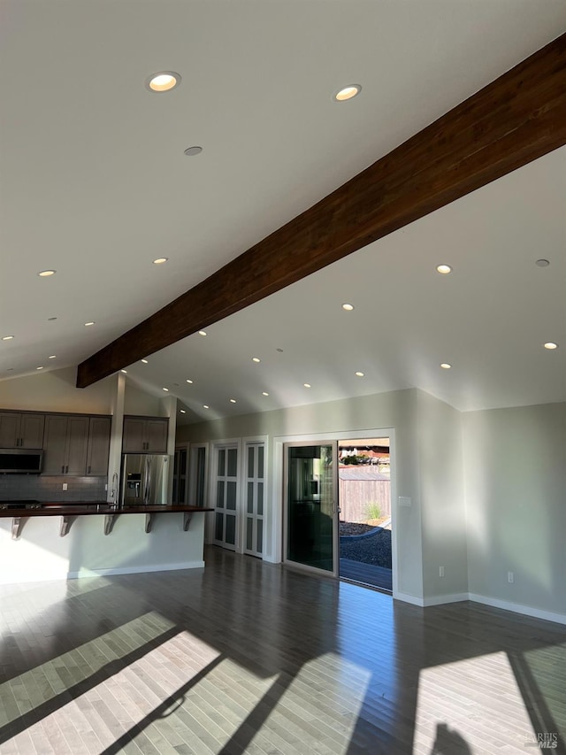 unfurnished living room featuring vaulted ceiling with beams and hardwood / wood-style flooring