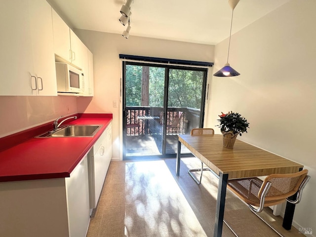 kitchen featuring pendant lighting, white cabinetry, and sink