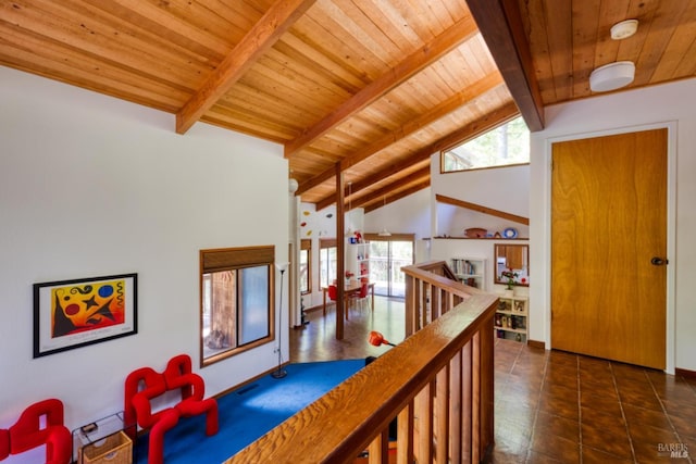 hall featuring beam ceiling, high vaulted ceiling, dark tile patterned flooring, and wooden ceiling