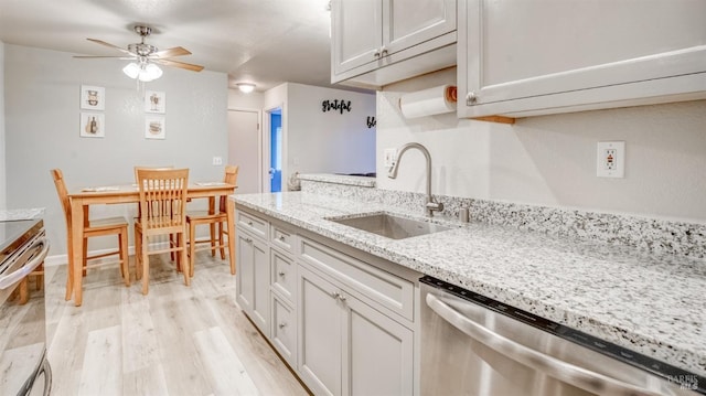 kitchen with ceiling fan, light hardwood / wood-style flooring, light stone counters, sink, and dishwasher