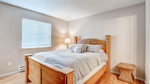 bedroom featuring a baseboard heating unit and light hardwood / wood-style flooring