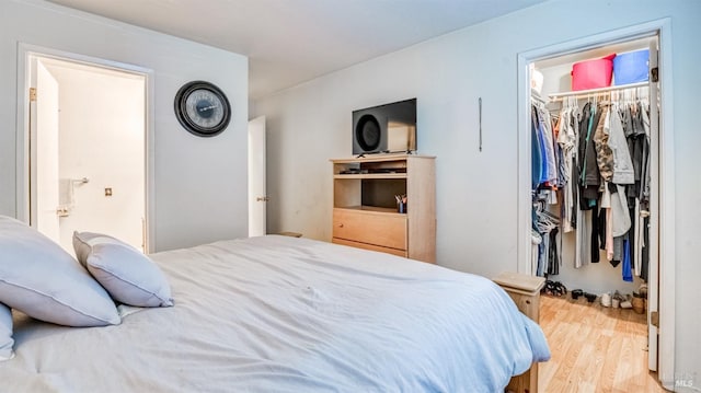 bedroom featuring wood-type flooring, a walk in closet, and a closet