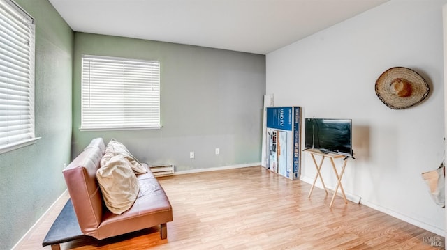 living area featuring plenty of natural light, a baseboard radiator, and light hardwood / wood-style floors