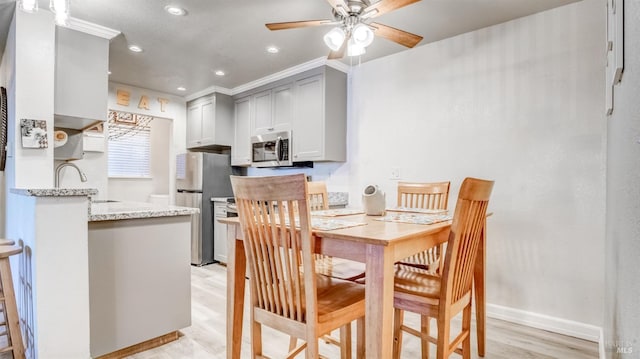 dining room featuring ceiling fan, sink, crown molding, and light wood-type flooring