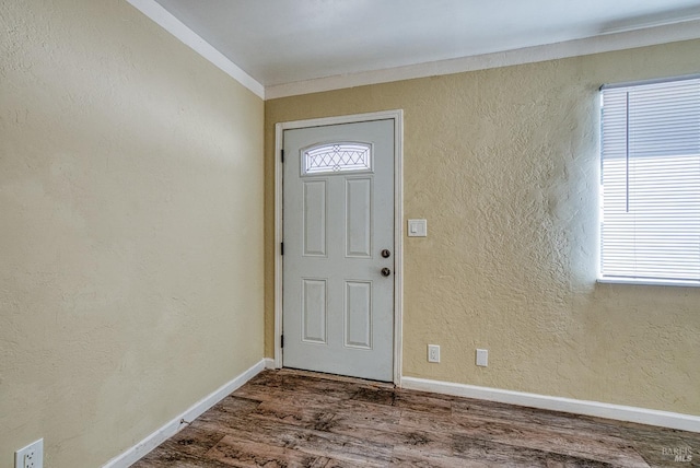 foyer featuring a wealth of natural light, ornamental molding, and hardwood / wood-style flooring