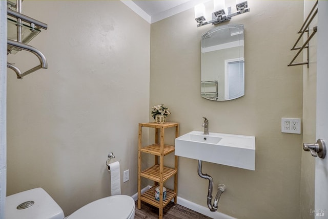 bathroom with ornamental molding, toilet, and hardwood / wood-style flooring