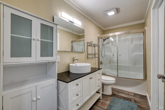 full bathroom featuring toilet, crown molding, vanity, bath / shower combo with glass door, and hardwood / wood-style flooring