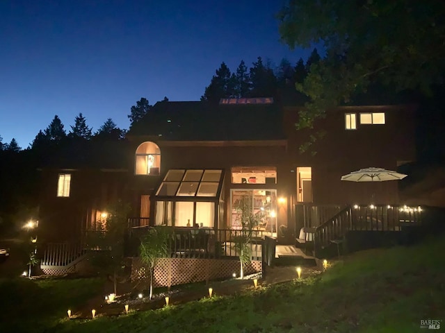 back house at twilight with a wooden deck