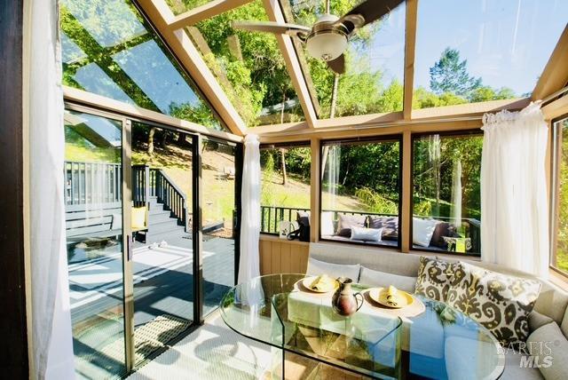 sunroom / solarium with ceiling fan, vaulted ceiling, and a wealth of natural light