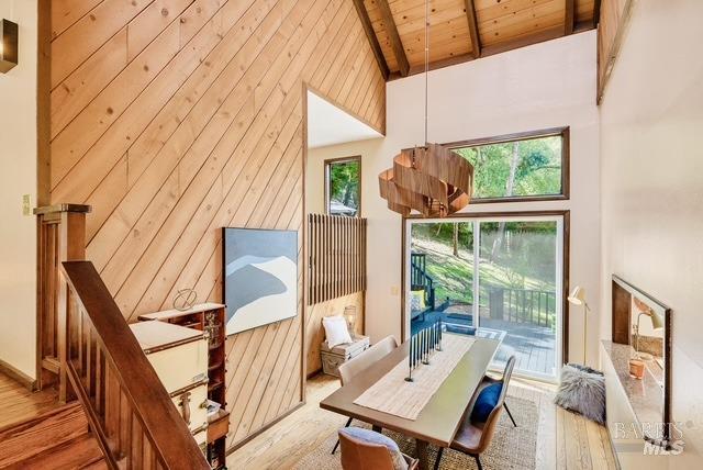 interior space featuring high vaulted ceiling, wooden ceiling, wood walls, wood finished floors, and beam ceiling