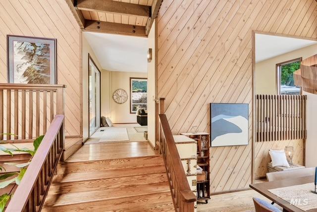 staircase featuring lofted ceiling with beams, wood walls, plenty of natural light, and wood finished floors