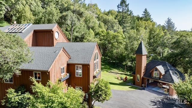 exterior space featuring board and batten siding, driveway, and a shingled roof