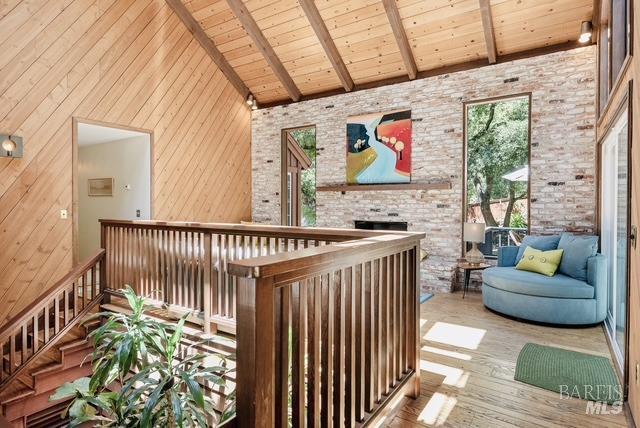 interior space featuring wood ceiling, an upstairs landing, wood finished floors, high vaulted ceiling, and beamed ceiling