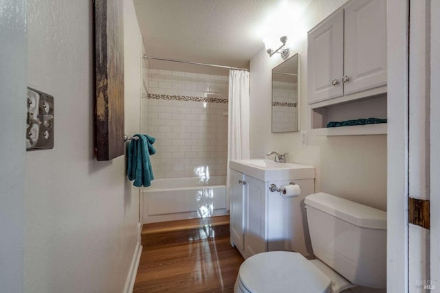 bathroom featuring toilet, wood finished floors, vanity, baseboards, and shower / bath combo