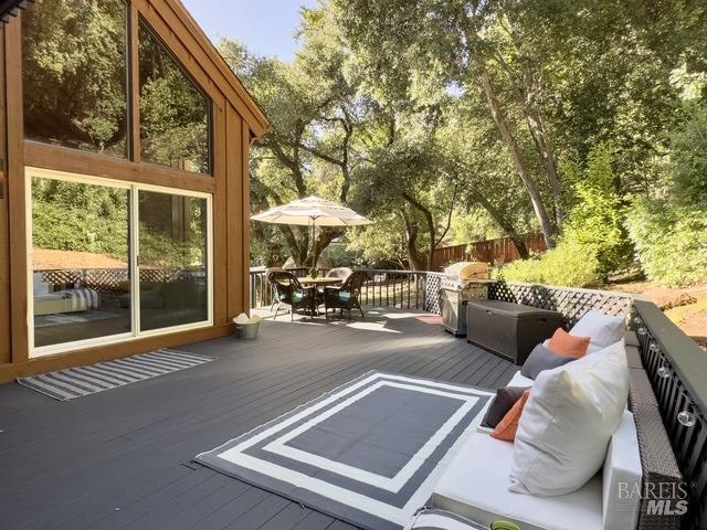 wooden deck featuring outdoor dining area, fence, grilling area, and an outdoor hangout area