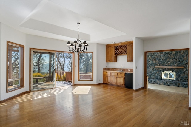 kitchen with a notable chandelier, light hardwood / wood-style flooring, a raised ceiling, and dishwasher