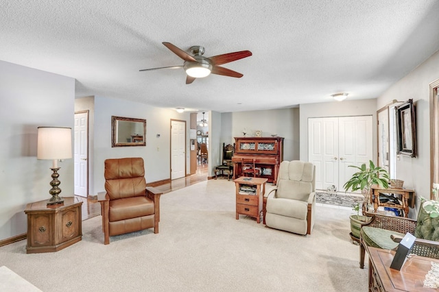 carpeted living room featuring ceiling fan and a textured ceiling