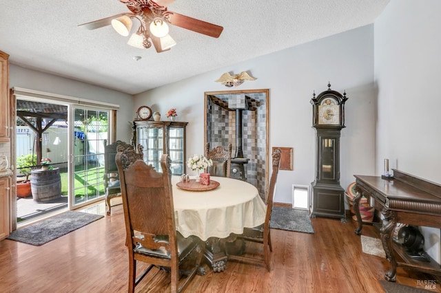 dining area with a textured ceiling, light hardwood / wood-style floors, and a wood stove