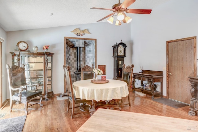 dining room featuring a textured ceiling, light wood-type flooring, ceiling fan, and vaulted ceiling