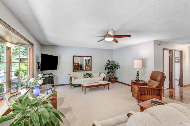 living room with ceiling fan, a textured ceiling, and light colored carpet