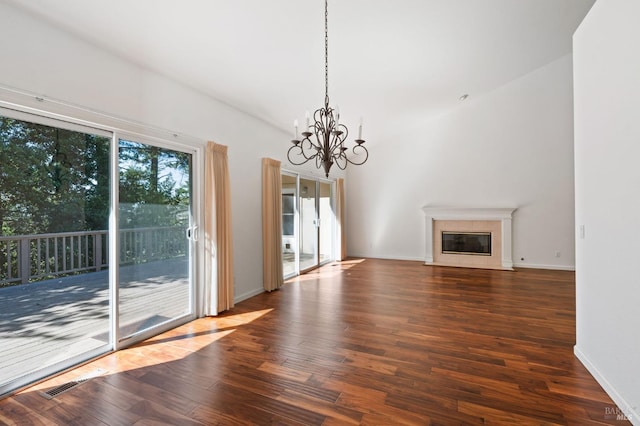 unfurnished living room with dark hardwood / wood-style floors, a notable chandelier, a fireplace, and a wealth of natural light