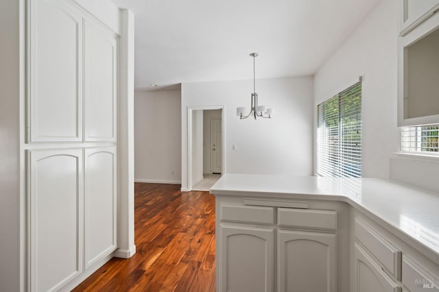 kitchen with a notable chandelier, white cabinets, wood-type flooring, and hanging light fixtures