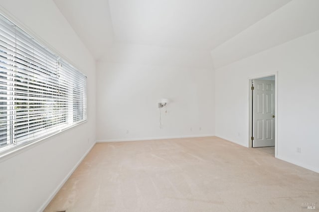 carpeted empty room with lofted ceiling