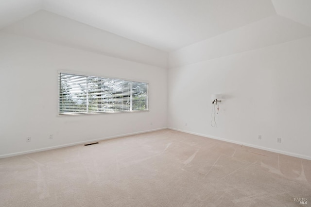 empty room with carpet flooring and vaulted ceiling