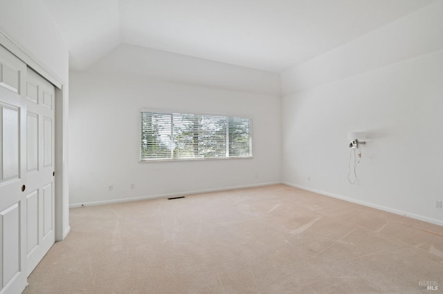 carpeted spare room featuring vaulted ceiling