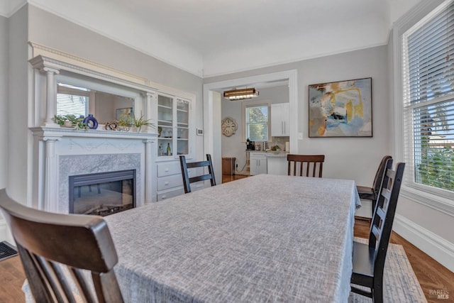 dining space with a premium fireplace, baseboards, and wood finished floors