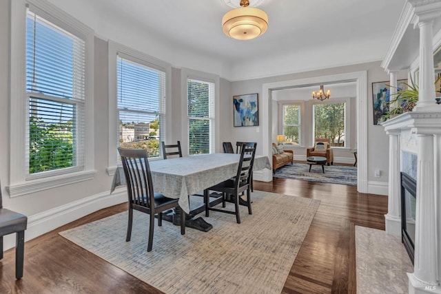 dining space featuring a notable chandelier, a fireplace, dark wood finished floors, and baseboards