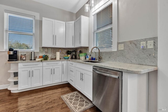 kitchen with dark wood finished floors, white cabinets, backsplash, stainless steel dishwasher, and a sink