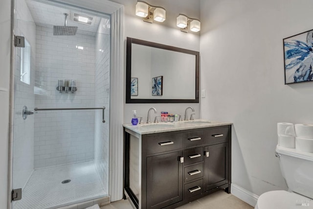 bathroom featuring double vanity, a stall shower, a sink, and toilet