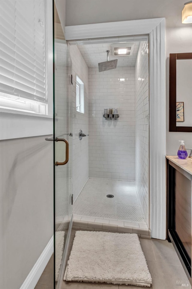 bathroom featuring a shower stall, baseboards, and tile patterned flooring