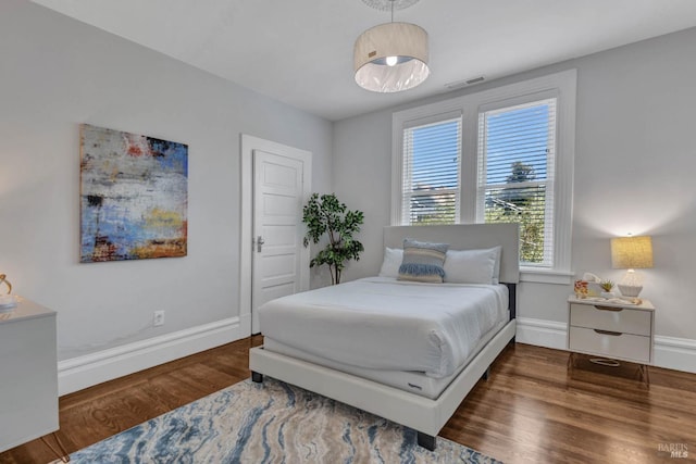 bedroom with wood finished floors, visible vents, and baseboards