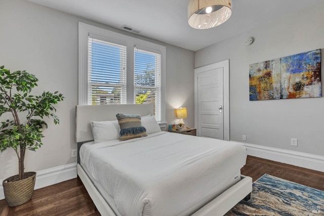 bedroom with baseboards, visible vents, and wood finished floors