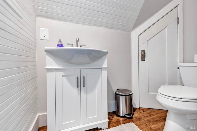 bathroom with toilet, vaulted ceiling, wood finished floors, and vanity