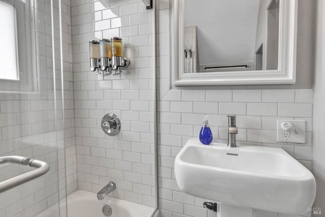 bathroom featuring washtub / shower combination, decorative backsplash, and a sink