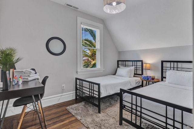 bedroom with lofted ceiling, wood finished floors, visible vents, and baseboards