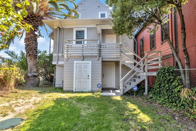 back of property featuring a yard, stairway, and fence